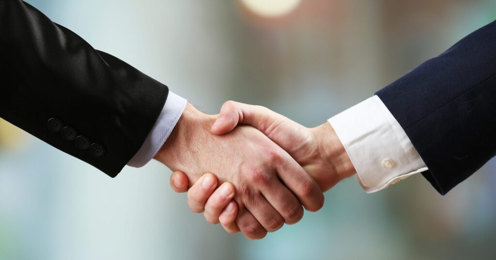 オークション取引成立を象徴するビジネスマン同士の信頼感のある握手
